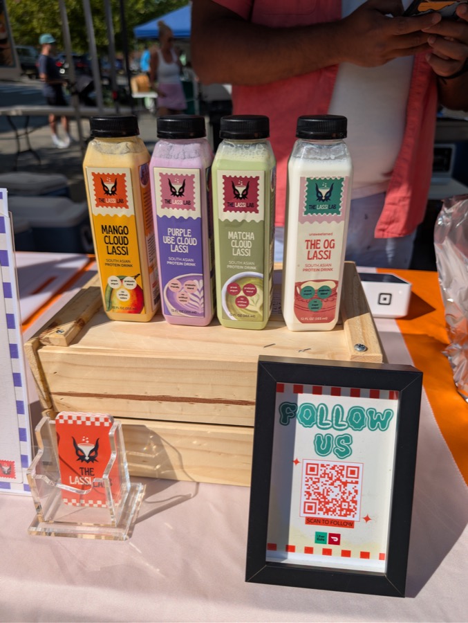 Four bottled lassis on a wooden crate at the stall: mango cloud, purple ube cloud, matcha cloud and the OG